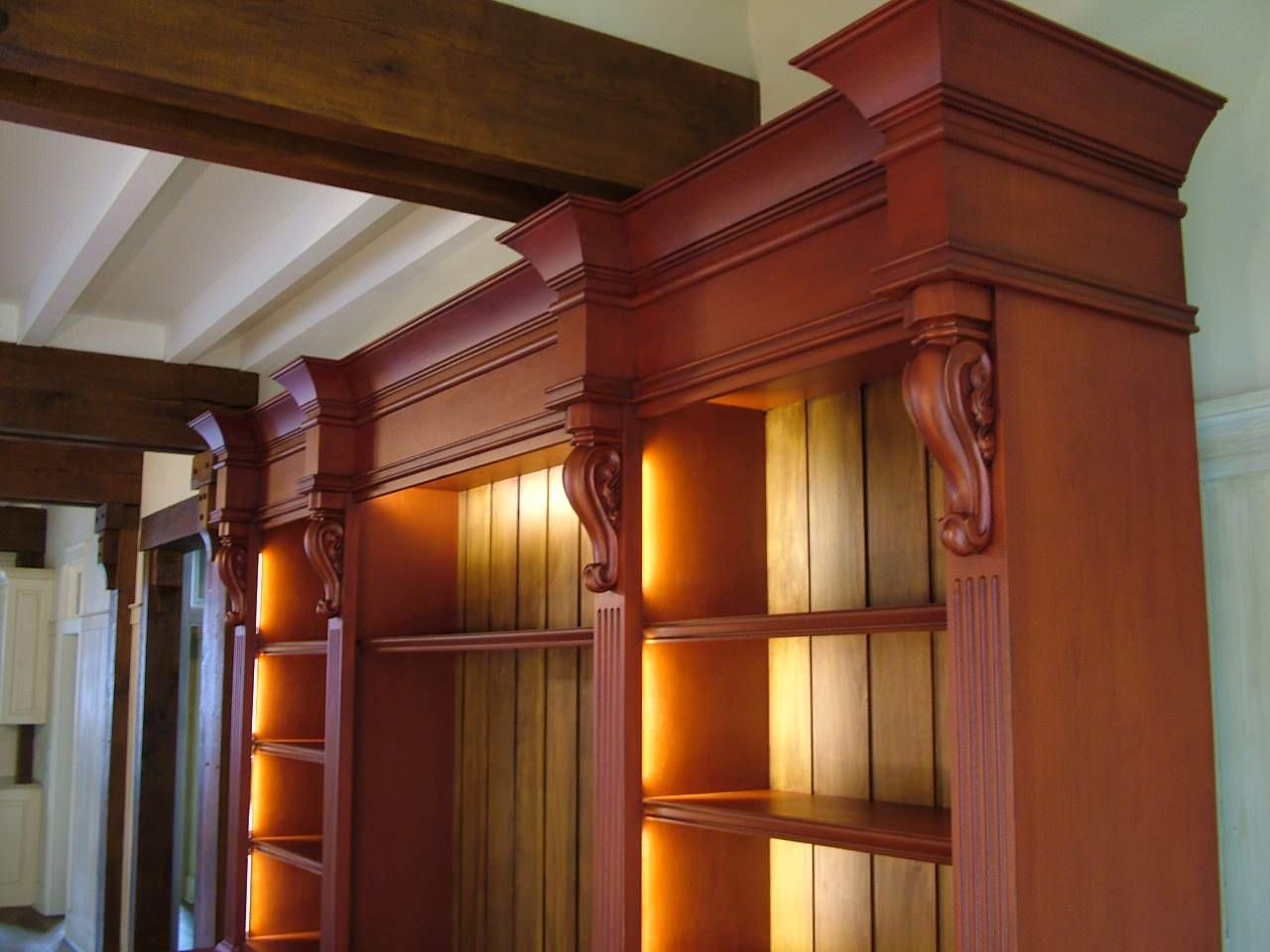 A wooden shelf with a light on the bottom shelf.