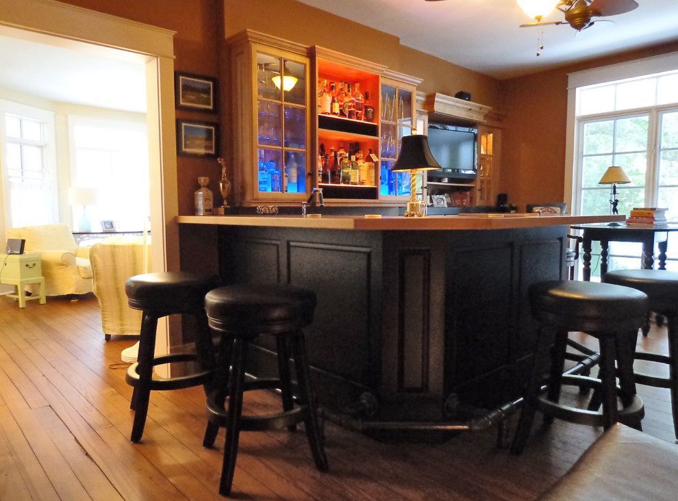 A bar in a living room with stools and a lamp.