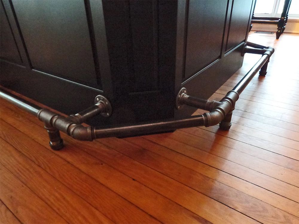 A corner of a wooden floor with pipes attached to it.