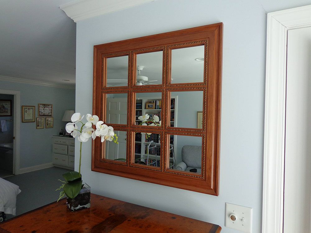 A large mirror with a wooden frame is hanging on a wall in a living room.