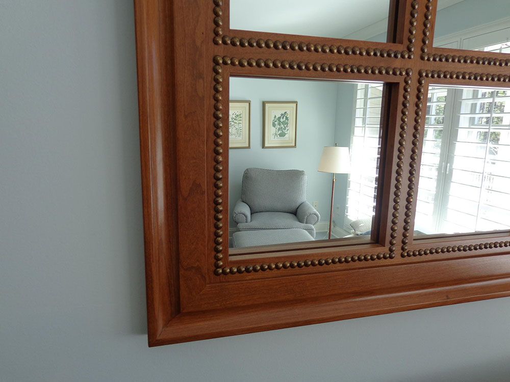 A large mirror with a wooden frame is hanging on a wall.