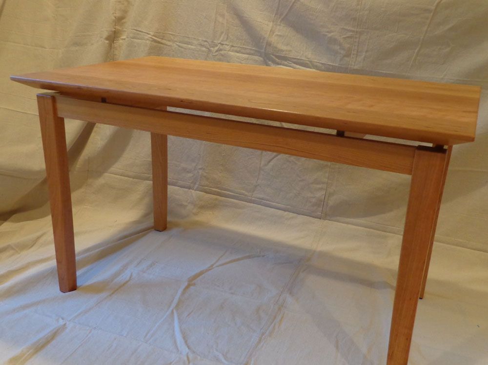 A small wooden table is sitting on a white cloth on a table.