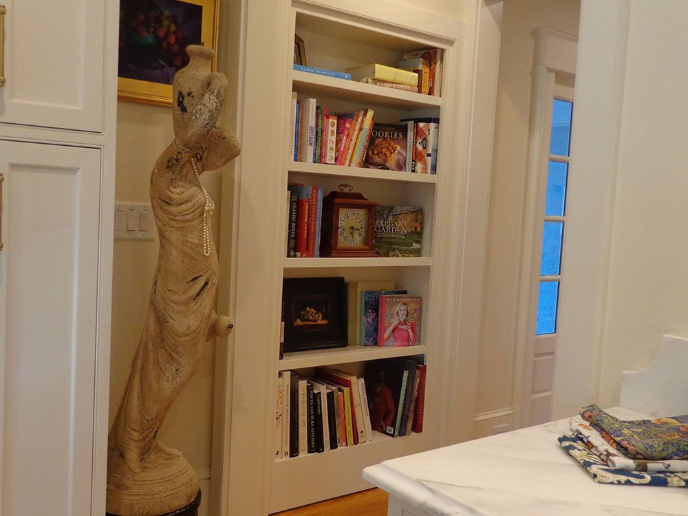 A statue of a woman stands next to a bookshelf filled with books.