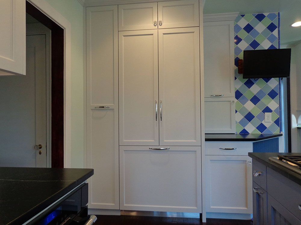 A kitchen with white cabinets and black countertops.