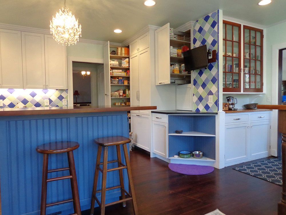 A kitchen with blue cabinets and wooden stools.