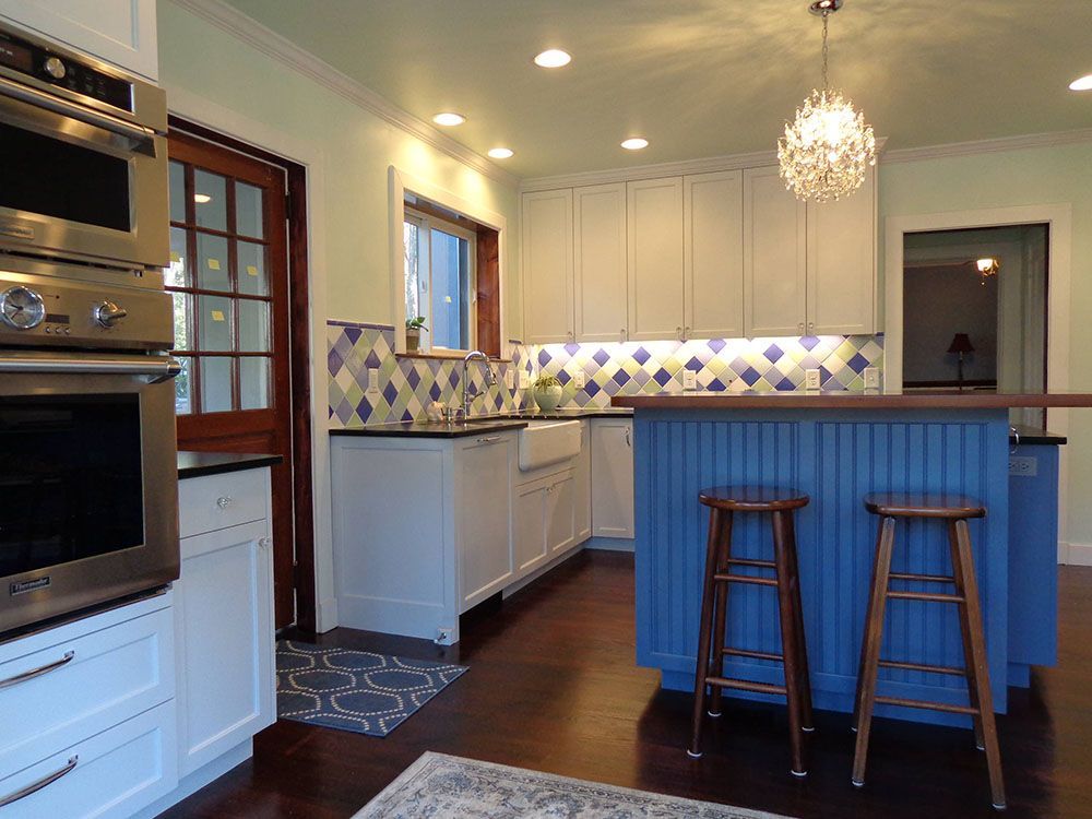 A kitchen with a blue island and two stools.