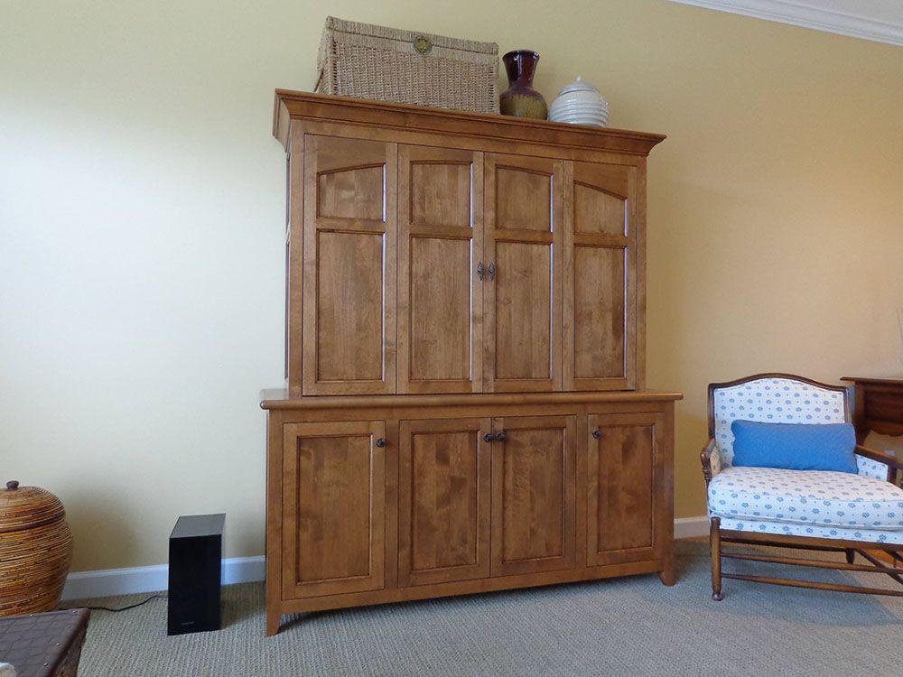 A living room with a large wooden cabinet and a chair.