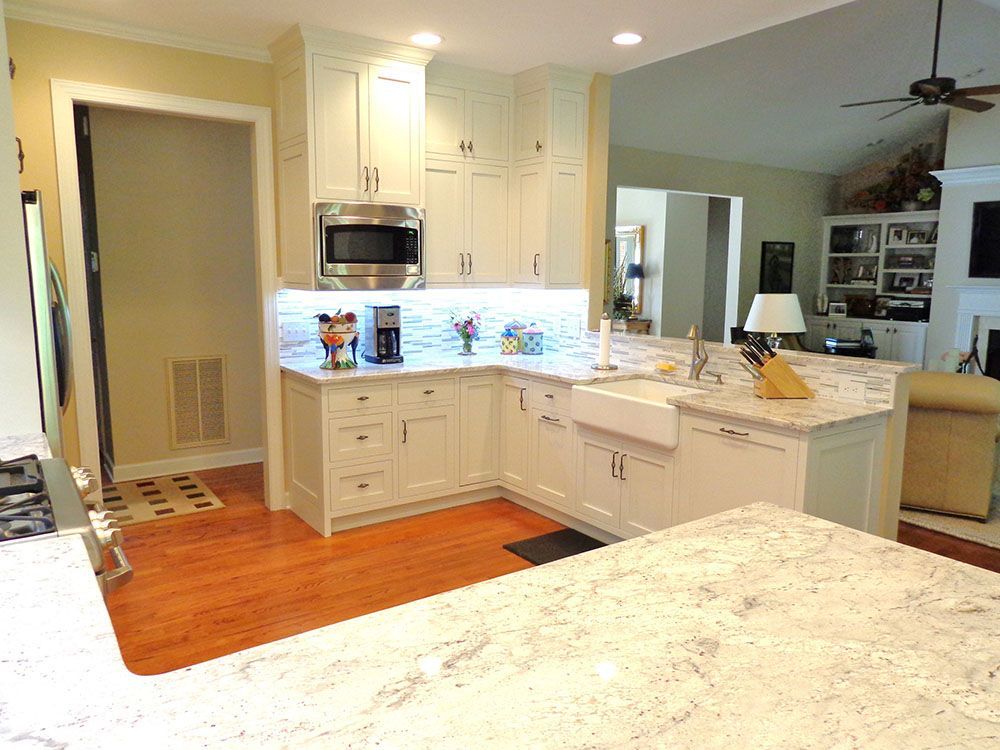 A kitchen with white cabinets, granite counter tops, a sink and a microwave.