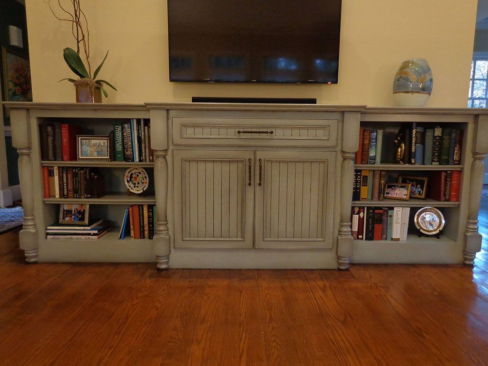 A living room with a large entertainment center filled with books and a flat-screen TV.