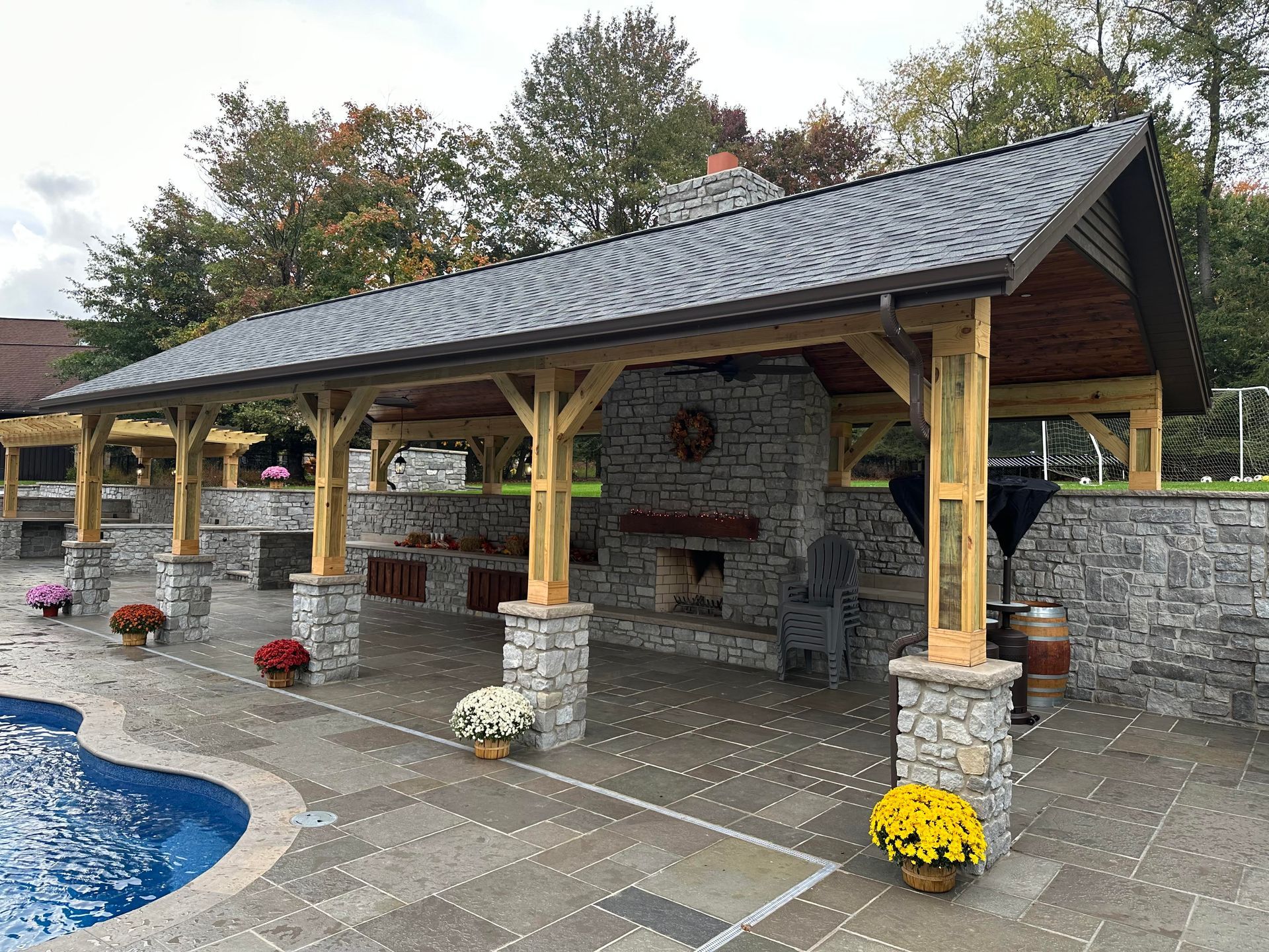 A large stone pavilion is sitting next to a swimming pool.