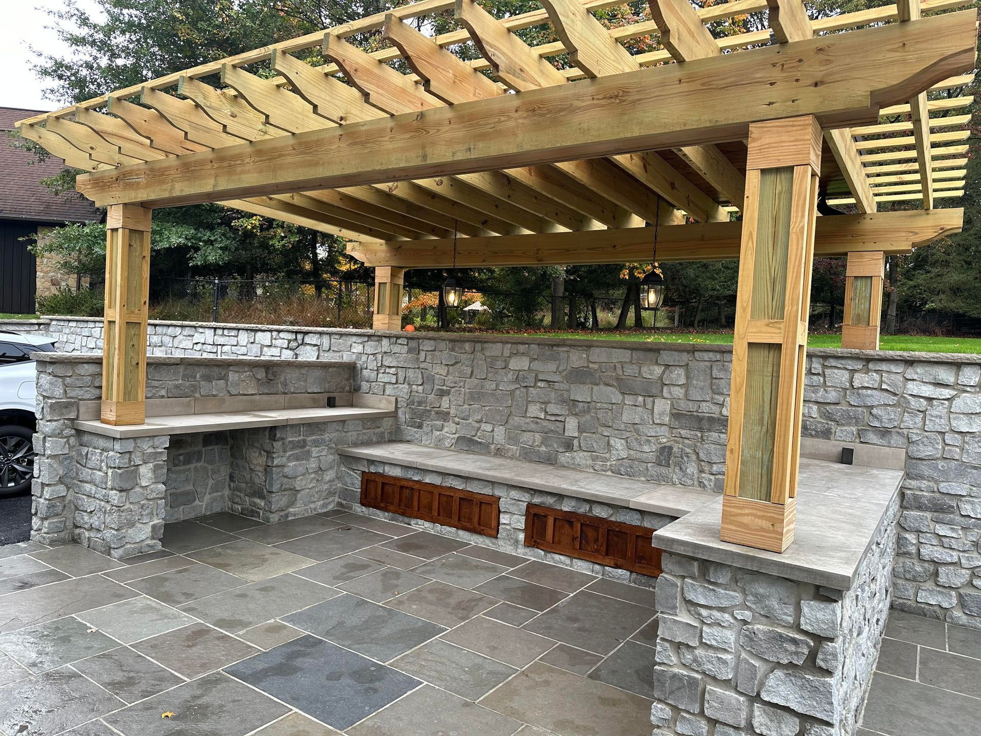 A wooden pergola is sitting on top of a stone patio.