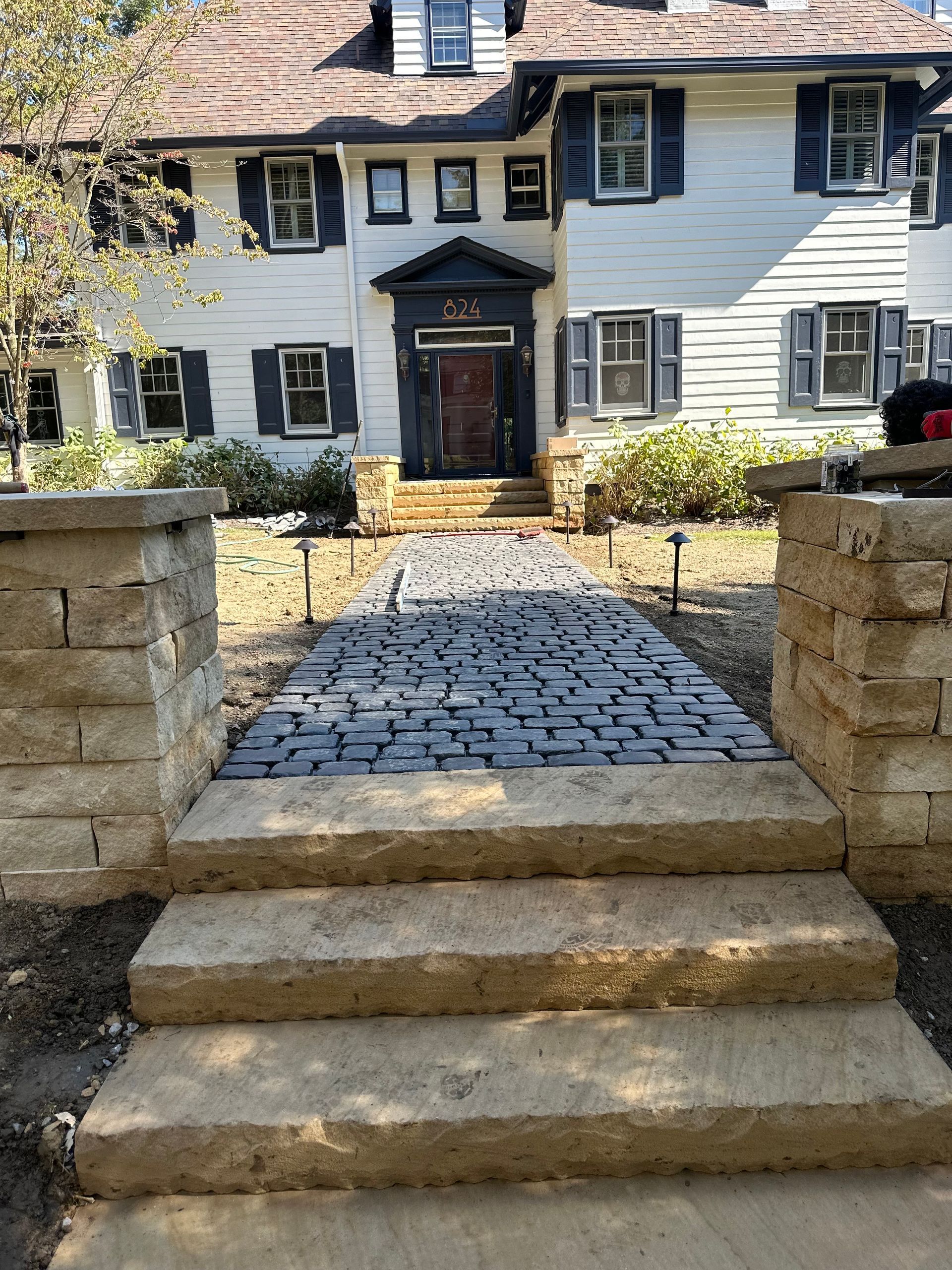 A white house with blue shutters and a stone walkway leading to the front door.