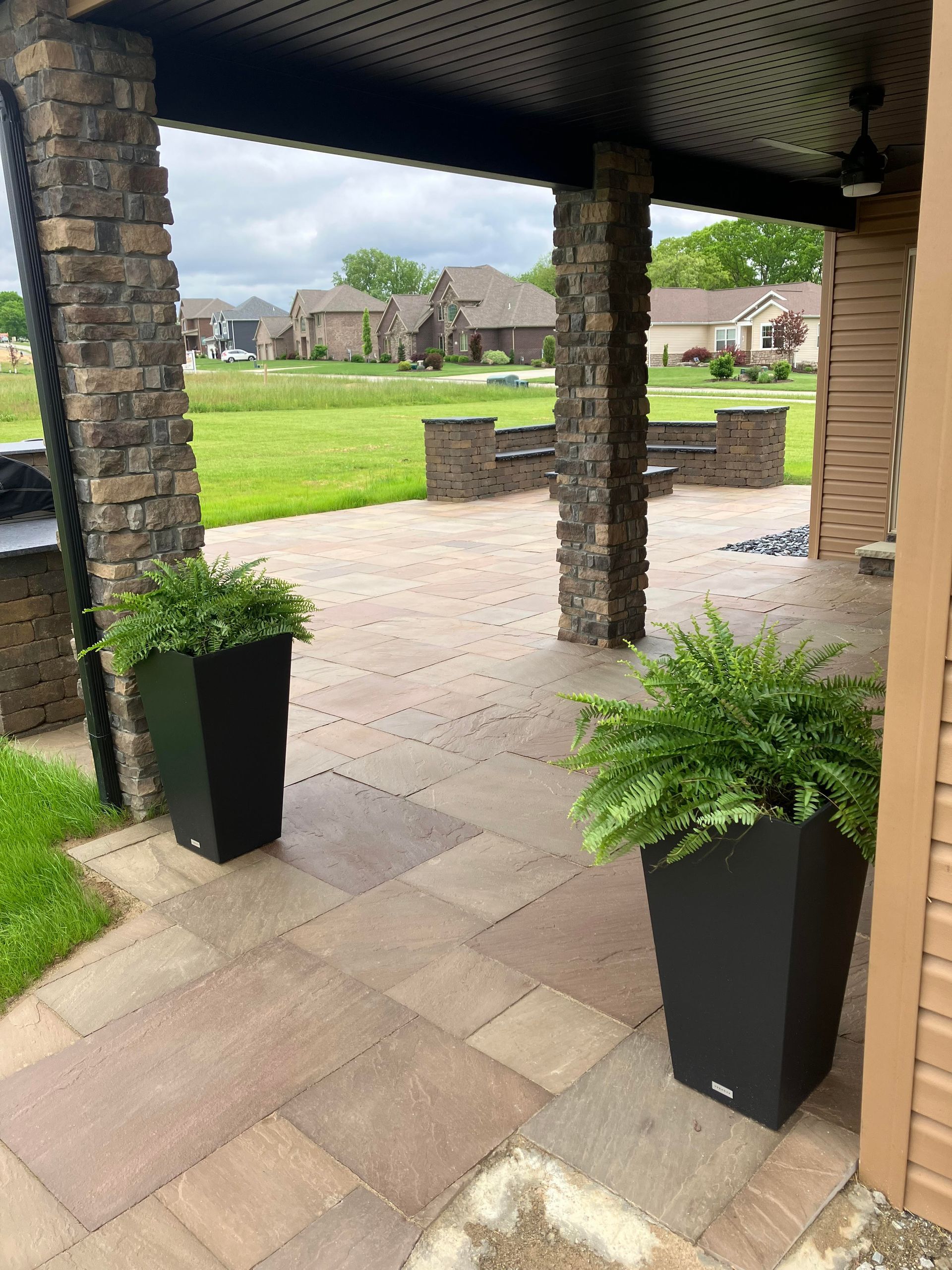 Two potted plants are sitting on a patio under a canopy.