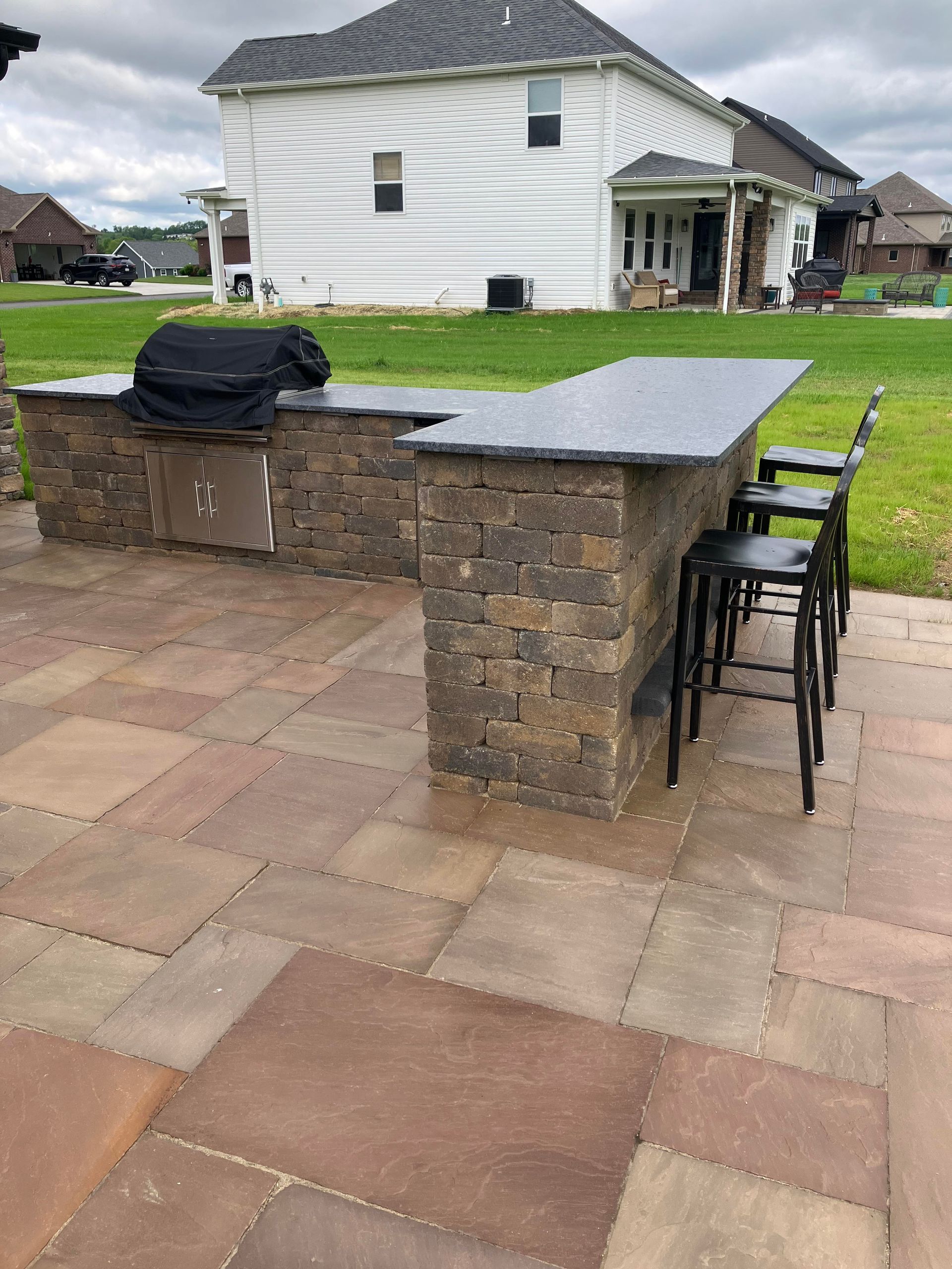 A patio with a grill and a bar in front of a house.