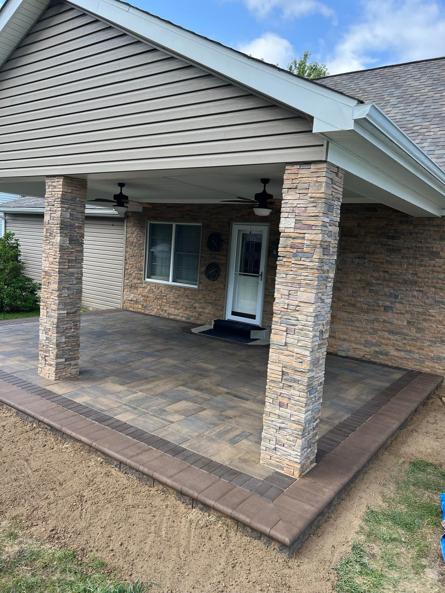 A house with a covered porch and a brick wall.