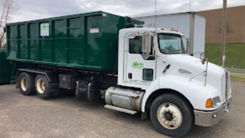 White cab green dump truck parked outdoors on a lot