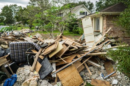 Damaged house and yard strewn with debris after storm or tornado