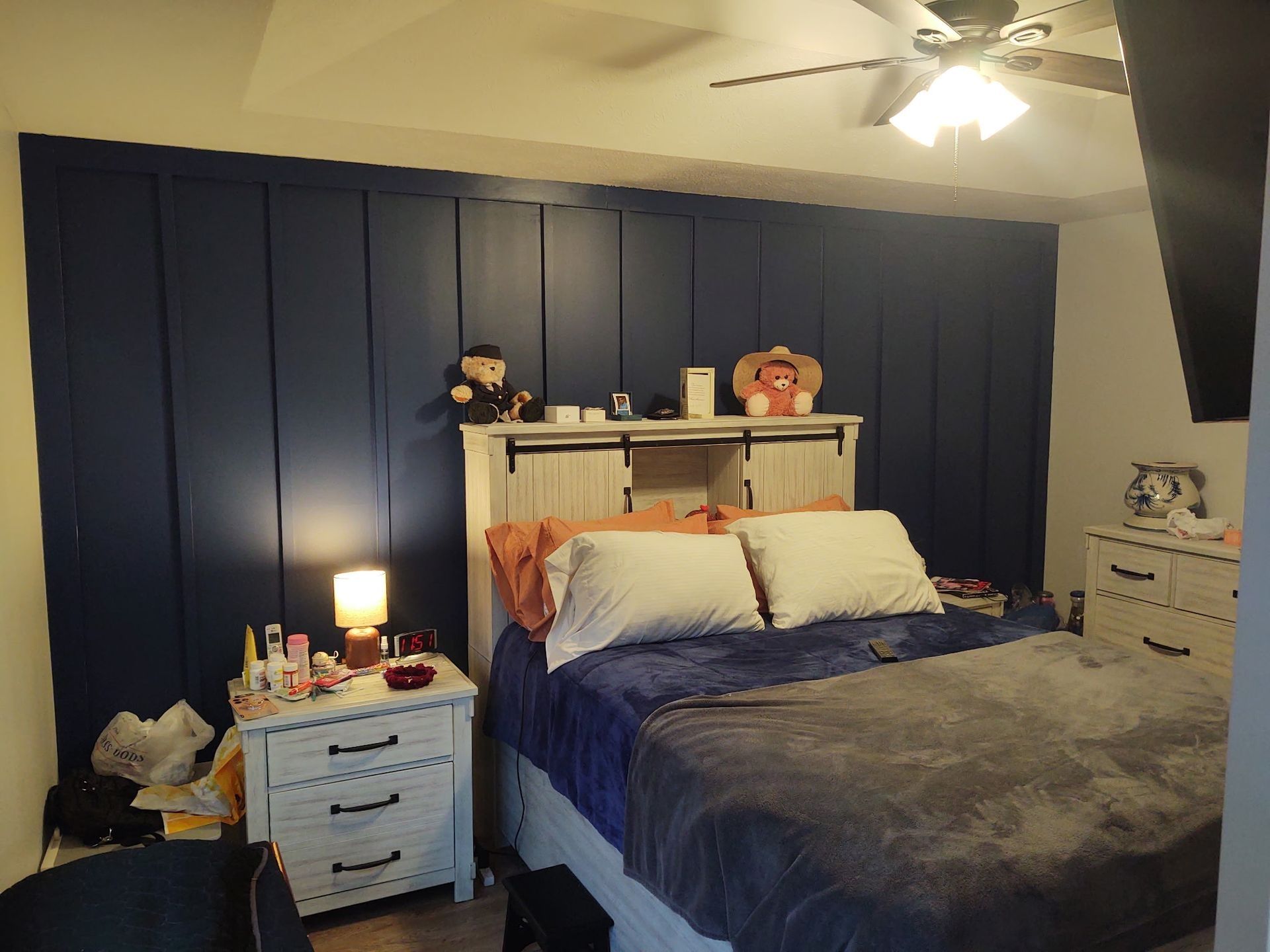 A bedroom with a bed , nightstand , dresser and ceiling fan.