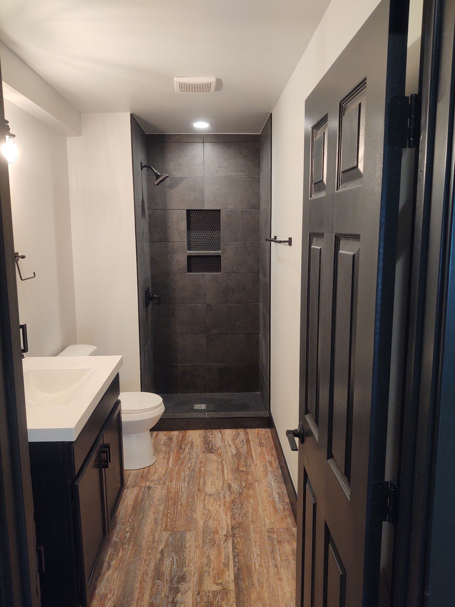Basement bathroom with a toilet, sink, and walk-in shower.