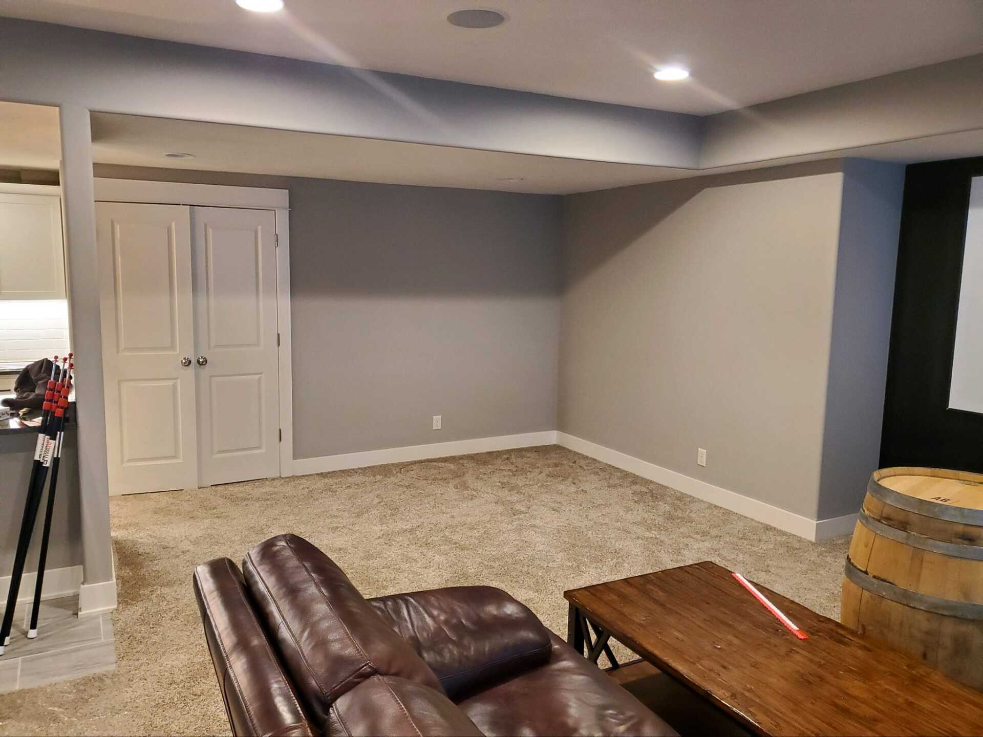 A living room in a basement with a couch and a table.