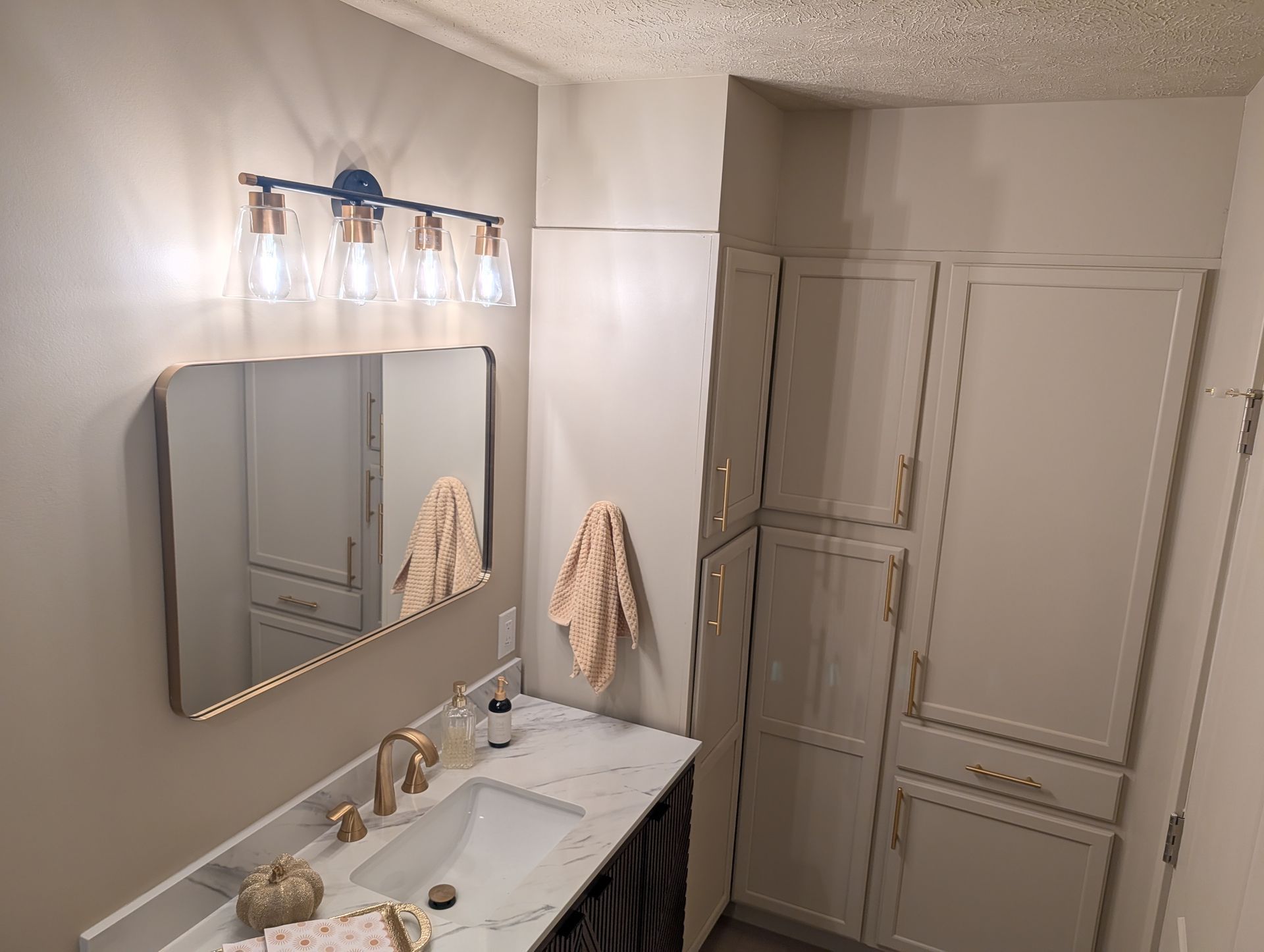 Bathroom with a vanity, mirror, cabinets, and a light fixture.
