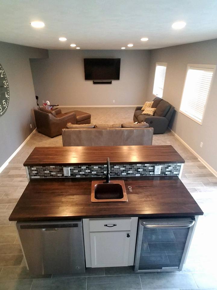 A kitchen with a sink and a refrigerator in a living room.