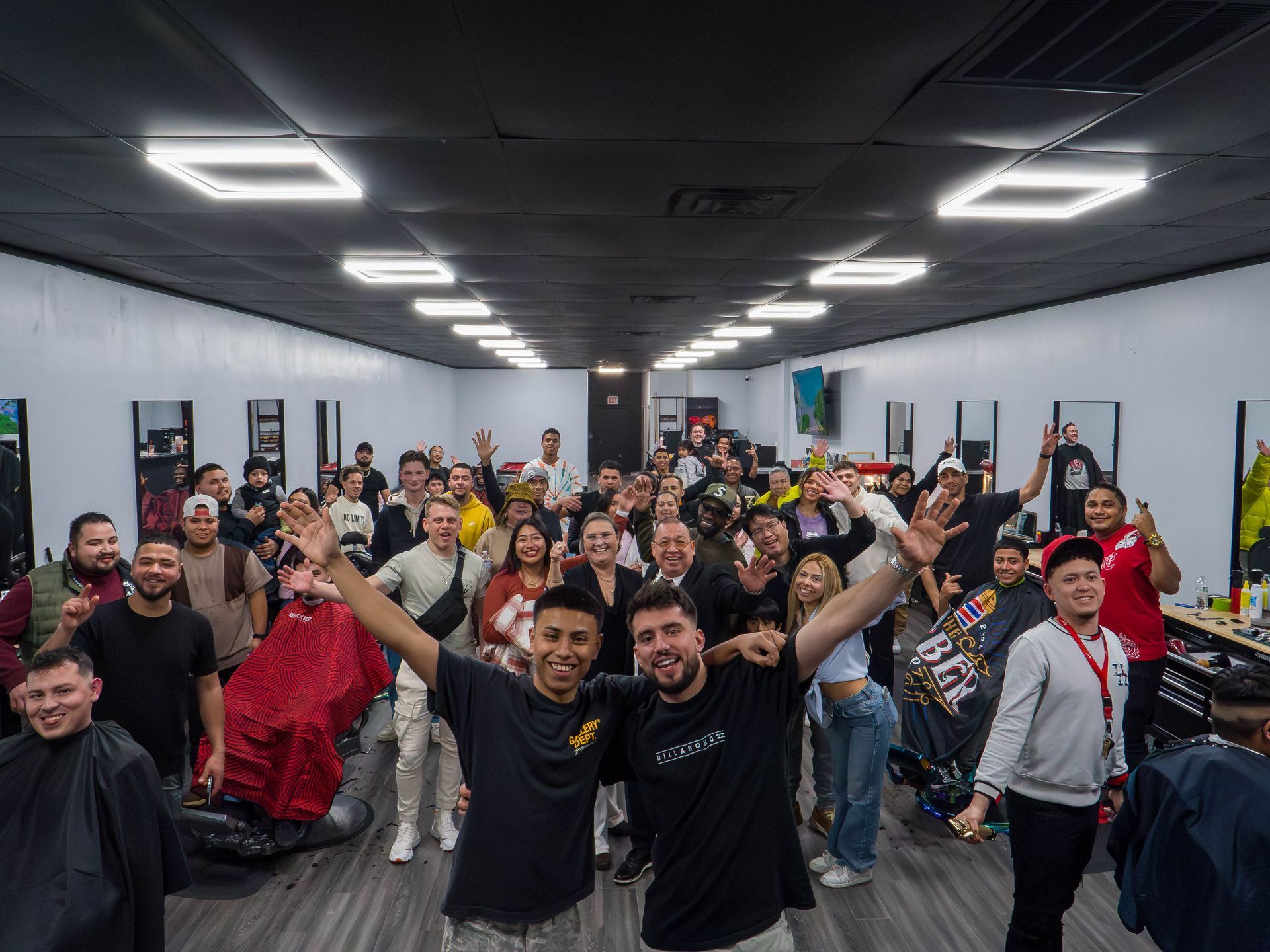 Large group posing and cheering in a modern indoor room with bright ceiling lights and posters on the walls