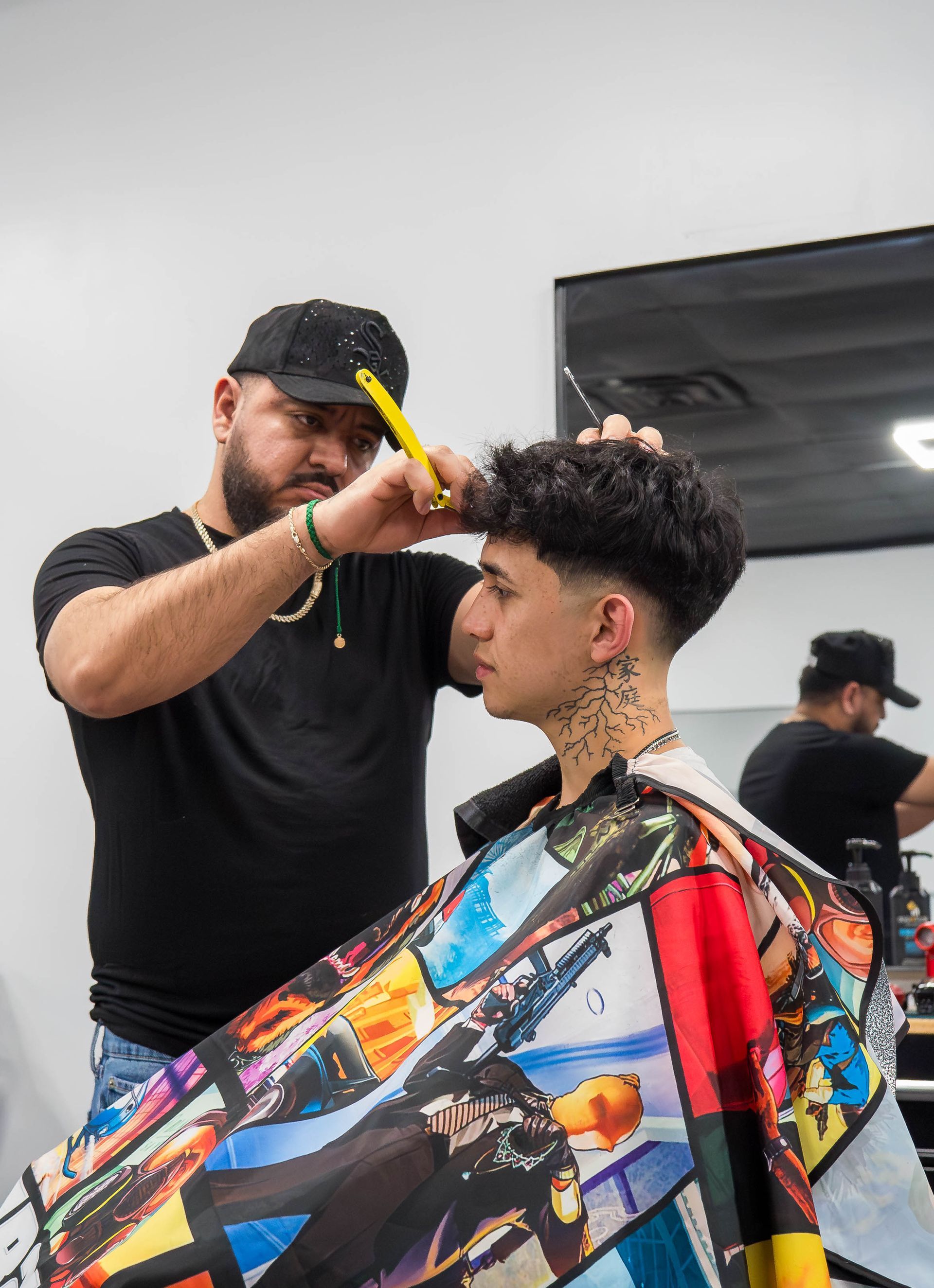 Barber trimming a client’s hair in a modern salon, with a colorful cape and mirror reflection.