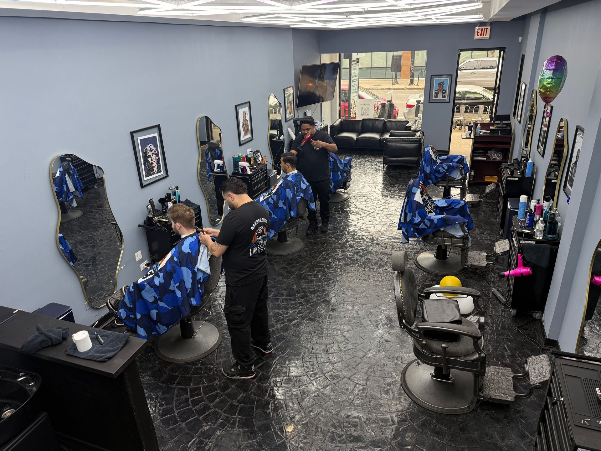 Barbershop interior with blue chairs, mirrors, and customers receiving haircuts