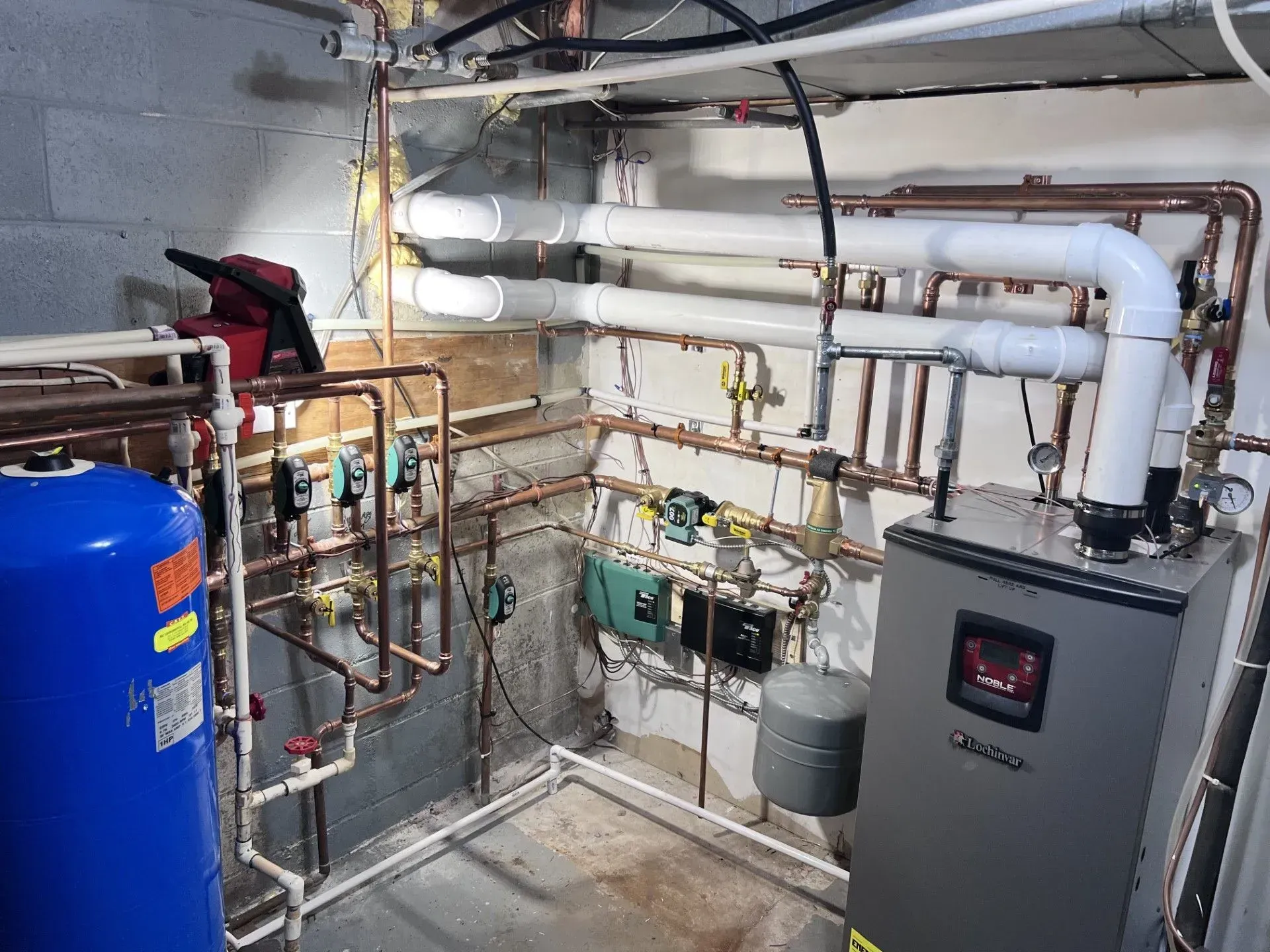 Basement utility room with boiler, water heater, copper pipes, and exposed plumbing on a concrete wall