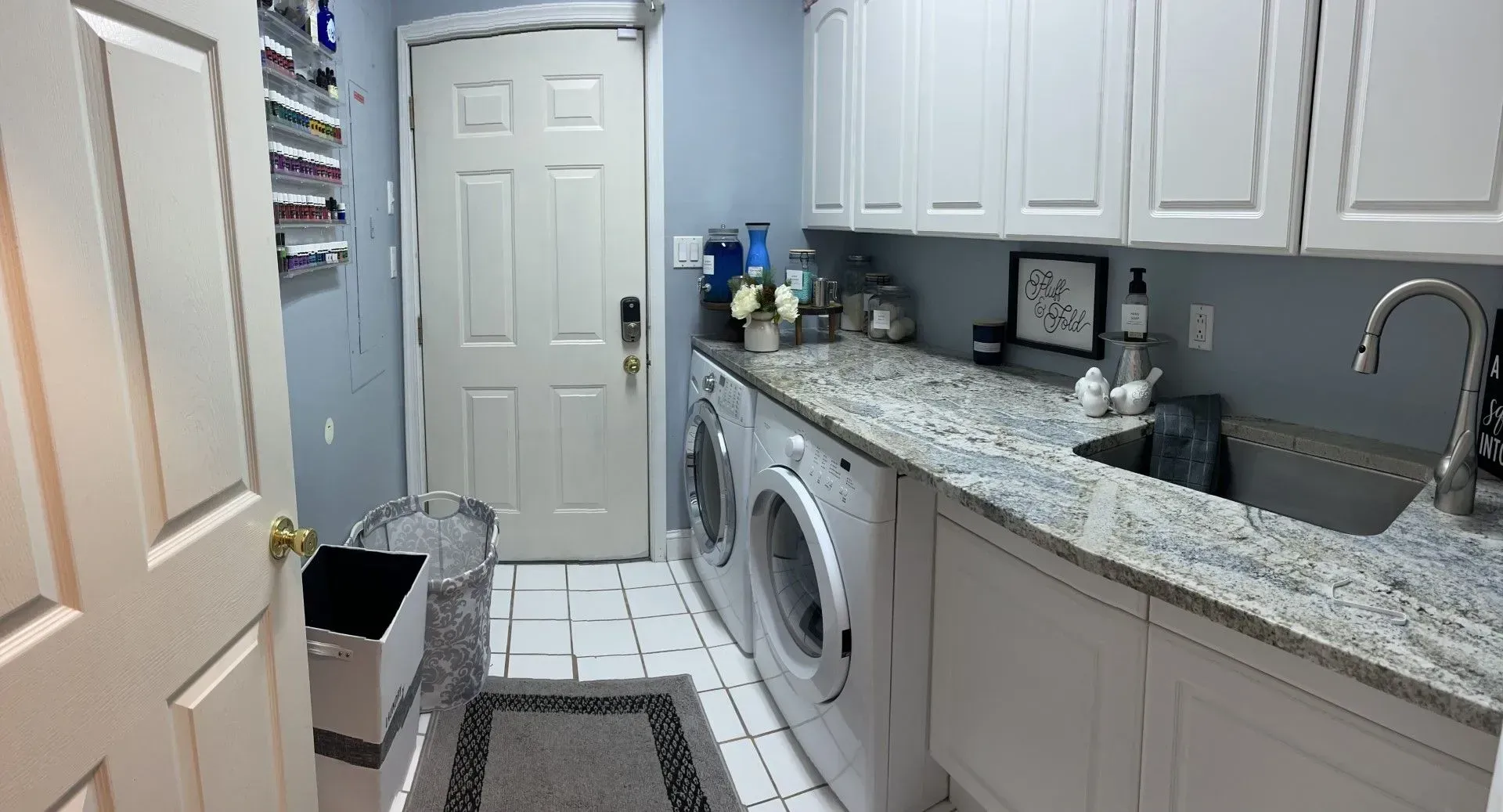 Narrow laundry room with white cabinets, granite counter, washer, sink, and tiled floor