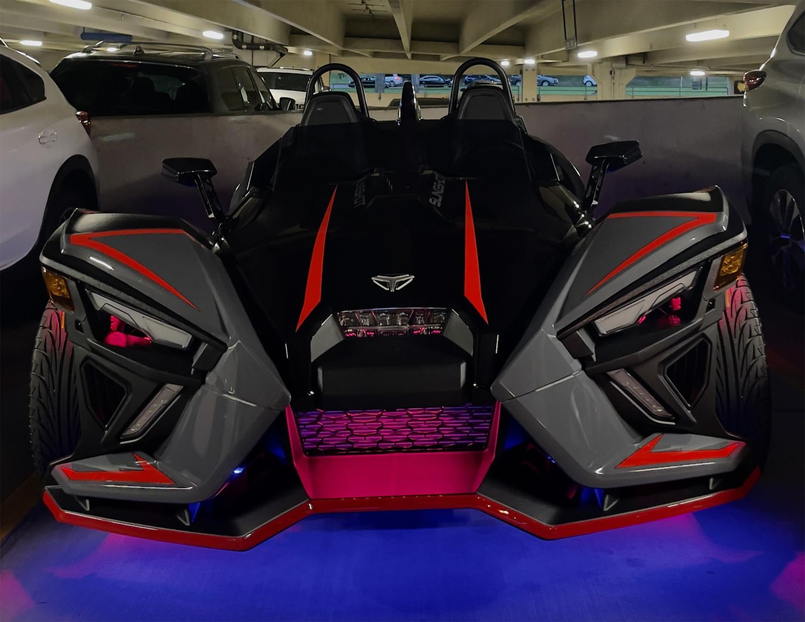 A slingshot is parked in a parking garage.