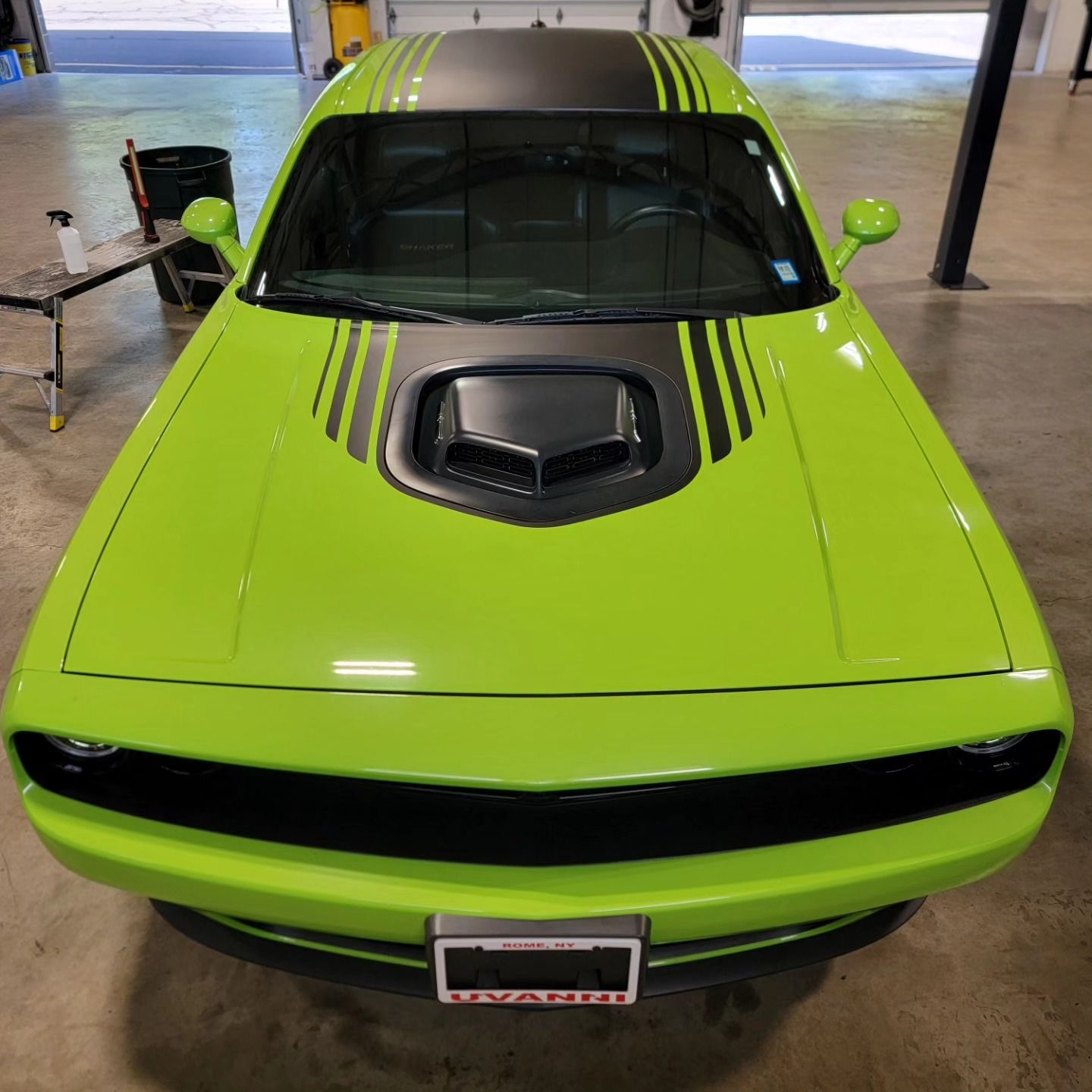 A green dodge challenger is parked in a garage
