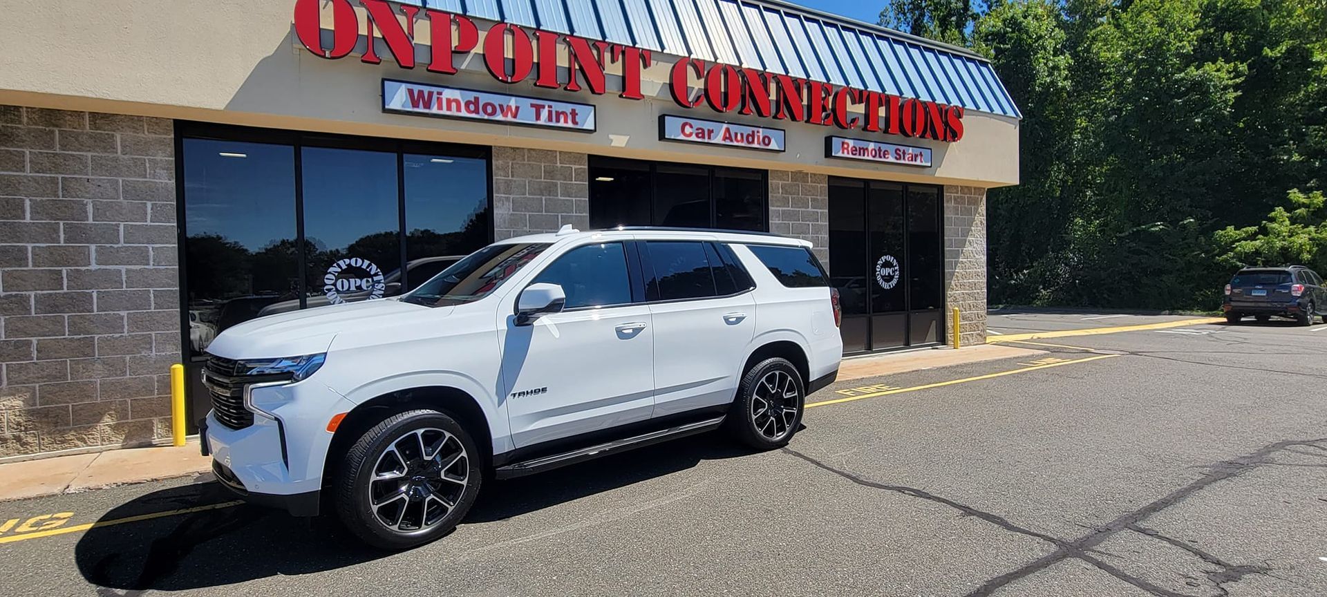 A white suv is parked in front of a car dealership.