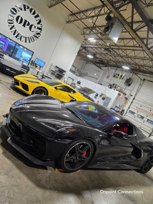 A black sports car is parked in a garage next to a yellow sports car