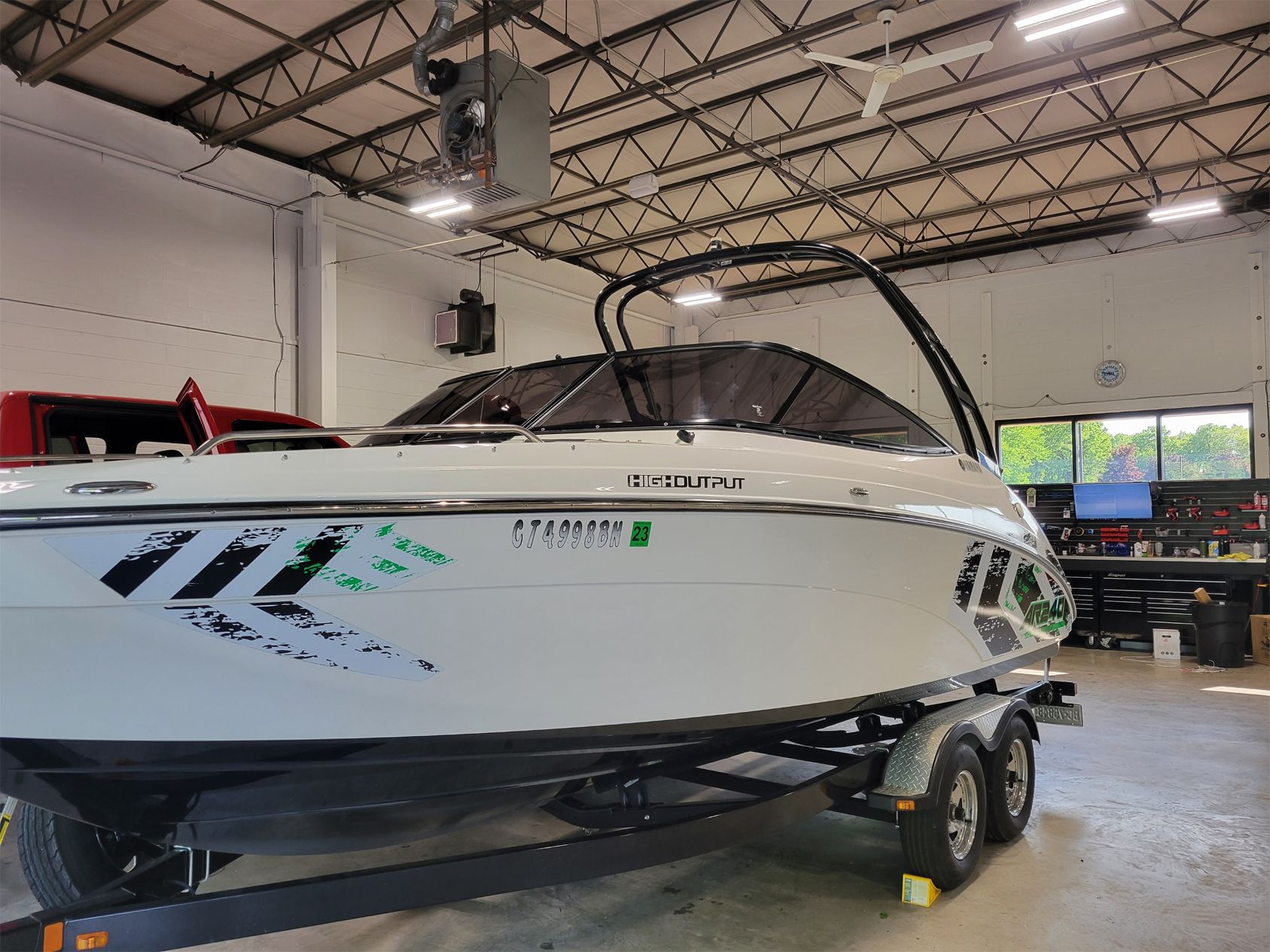 A white boat is parked on a trailer in a garage.