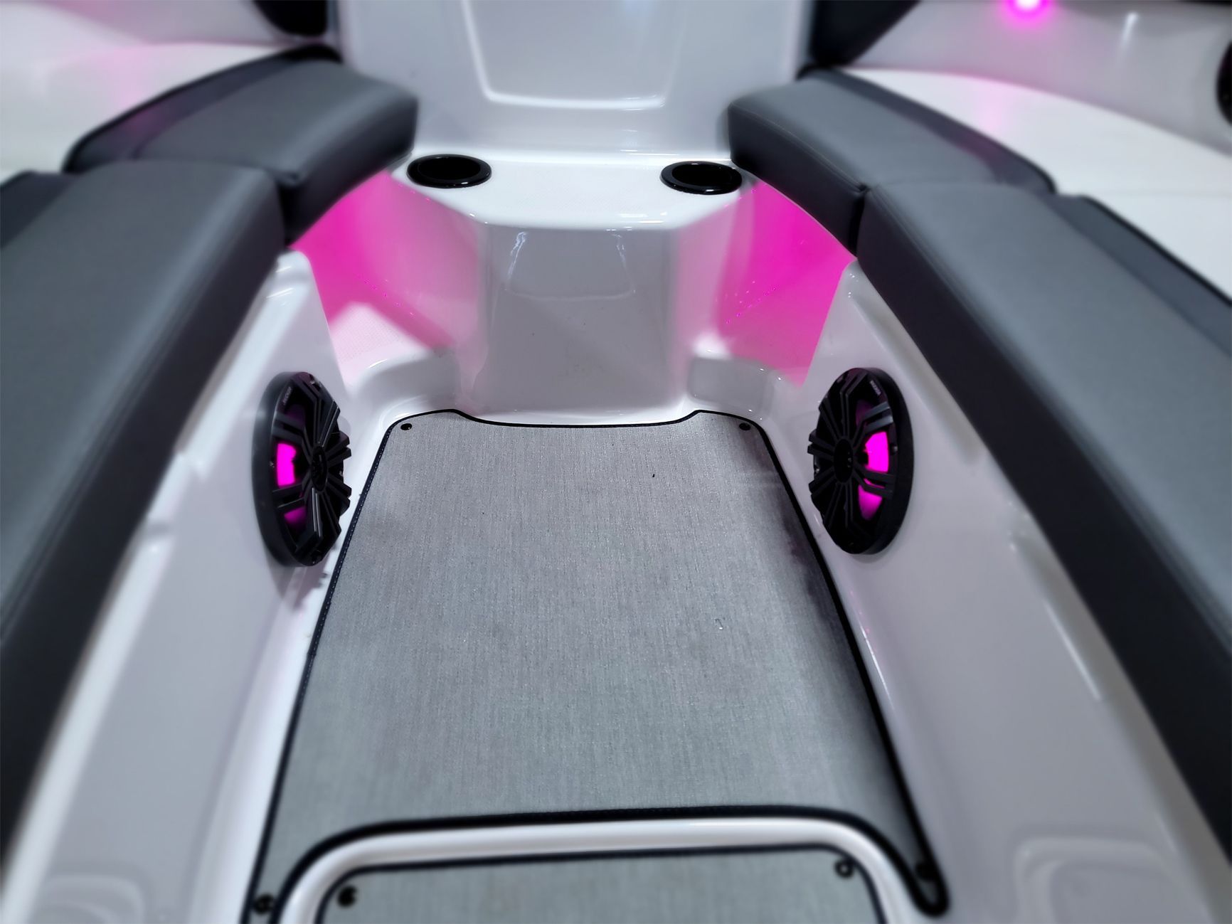 The inside of a boat with pink lights and speakers.