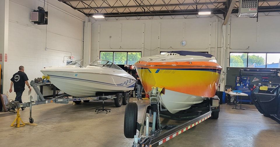 Two boats are sitting on a trailer in a garage.