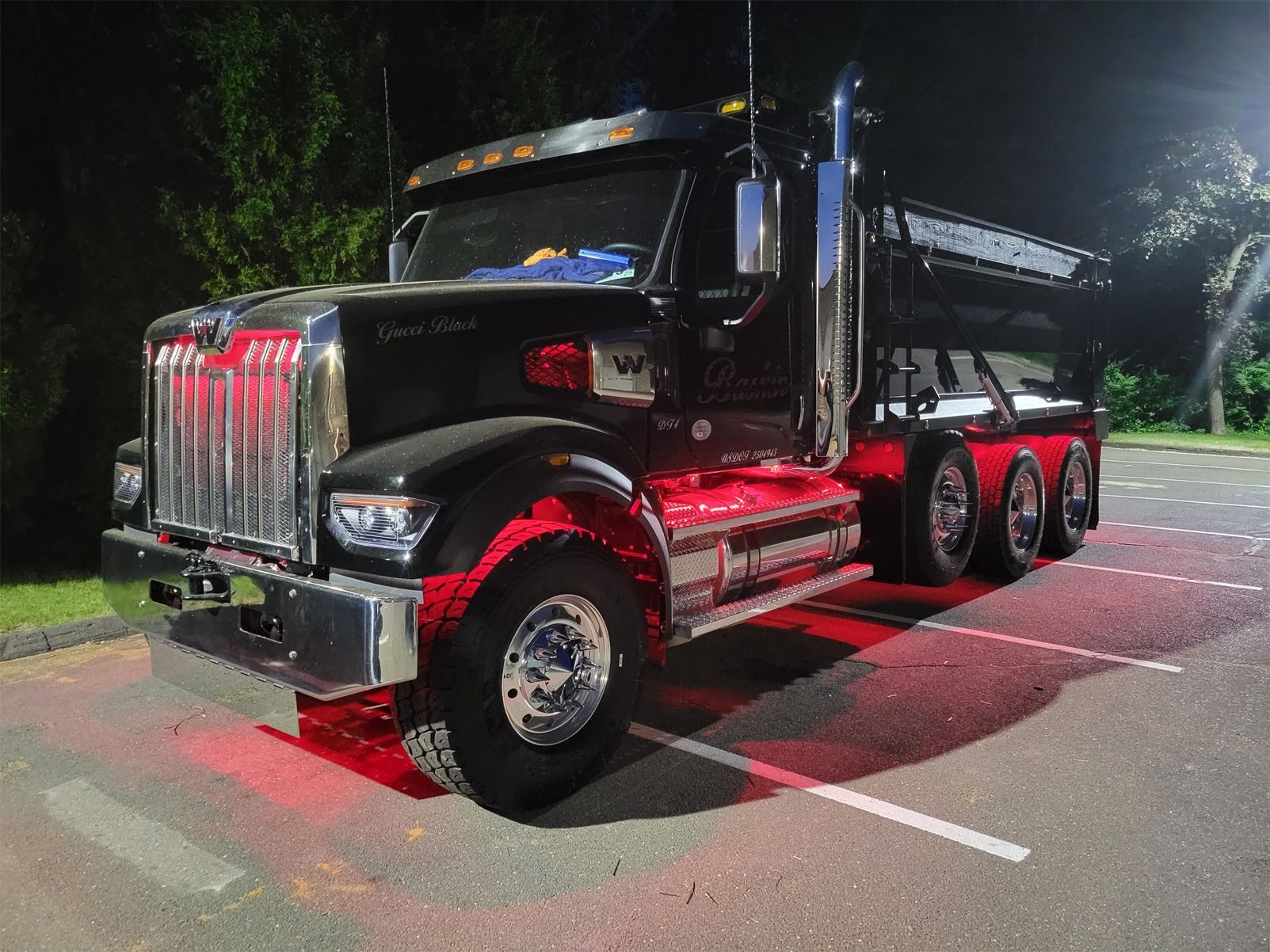 A dump truck is parked in a parking lot at night.