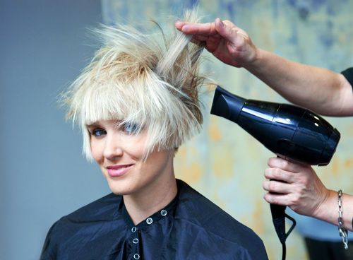 Blonde hair being blow-dried and styled with a round brush at a salon