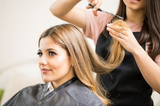 Hair stylist curling a client&rsquo;s blonde hair in a salon