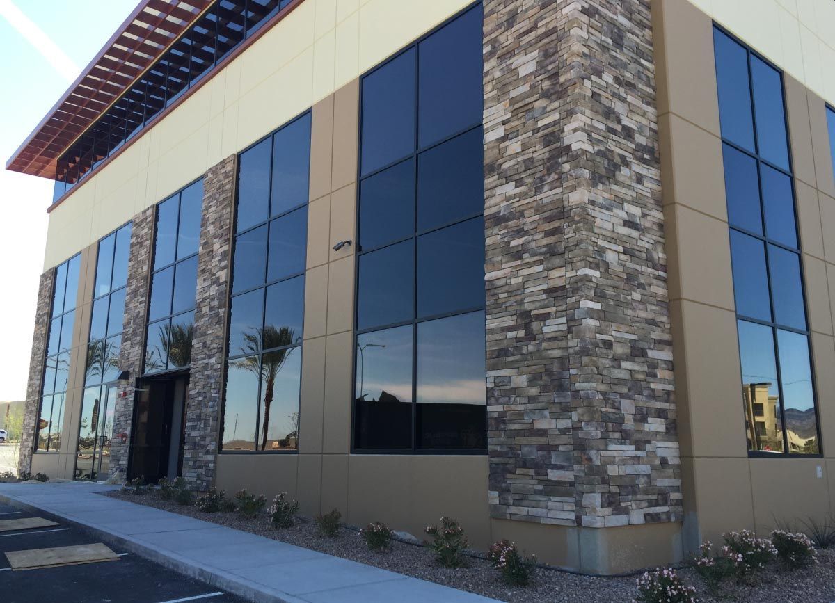 Two-story commercial building with large, tinted windows, stone accents, and a beige facade.
