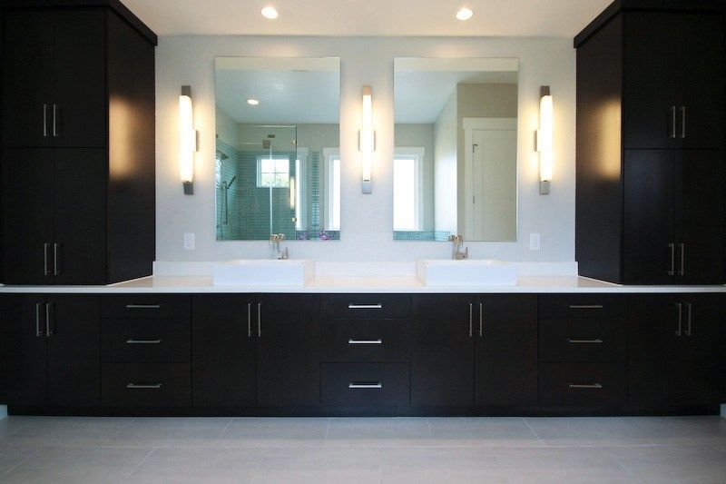 Modern black bathroom vanity with two sinks, mirrors, and cabinets.