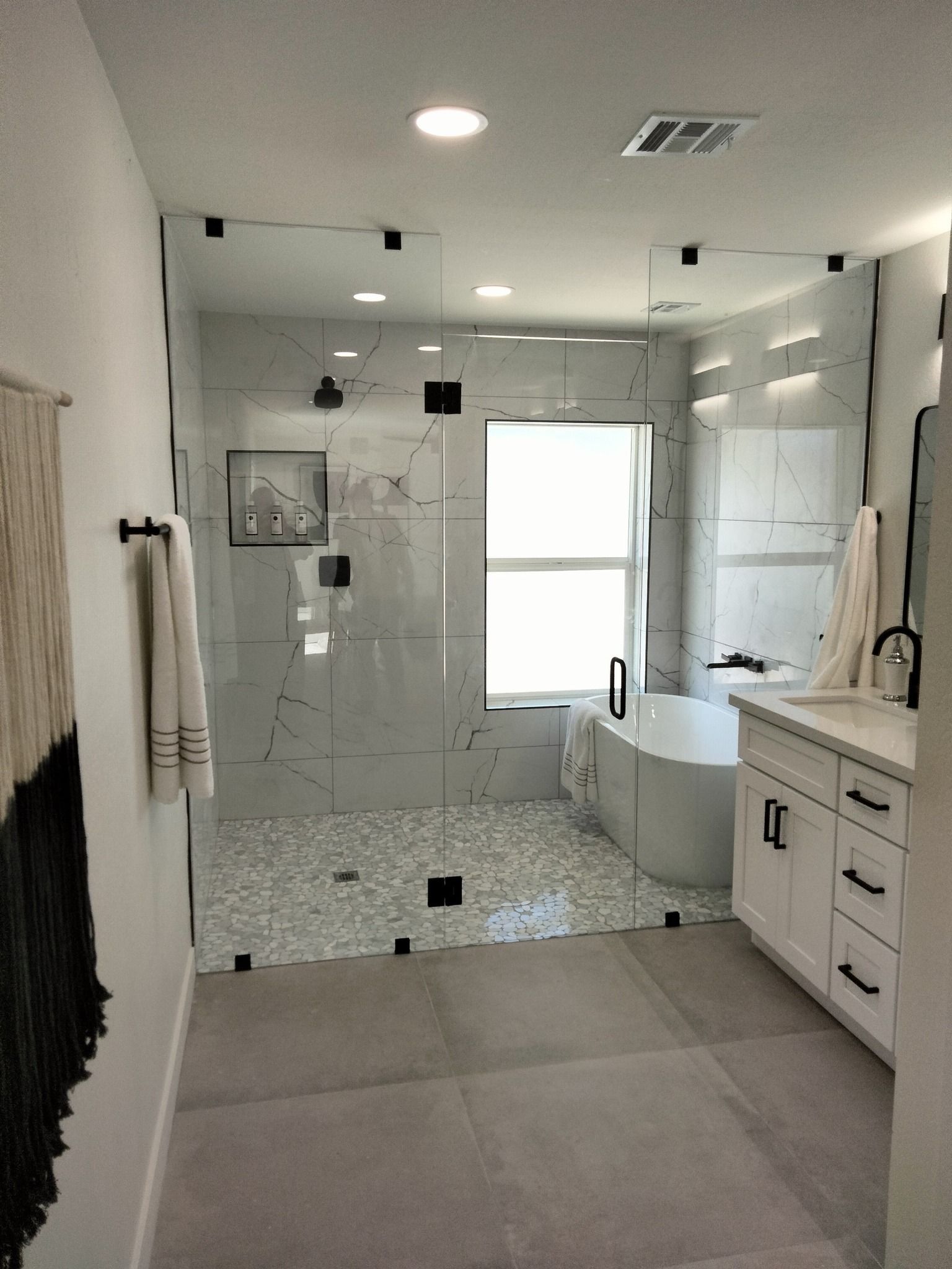 Modern bathroom with a glass shower, white tile, tub, and vanity.