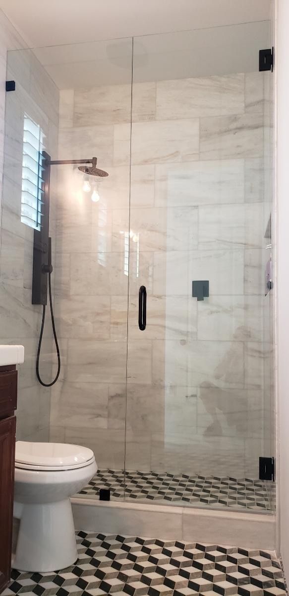 Bathroom with glass shower door, white marble tile, black and white checkered floor.