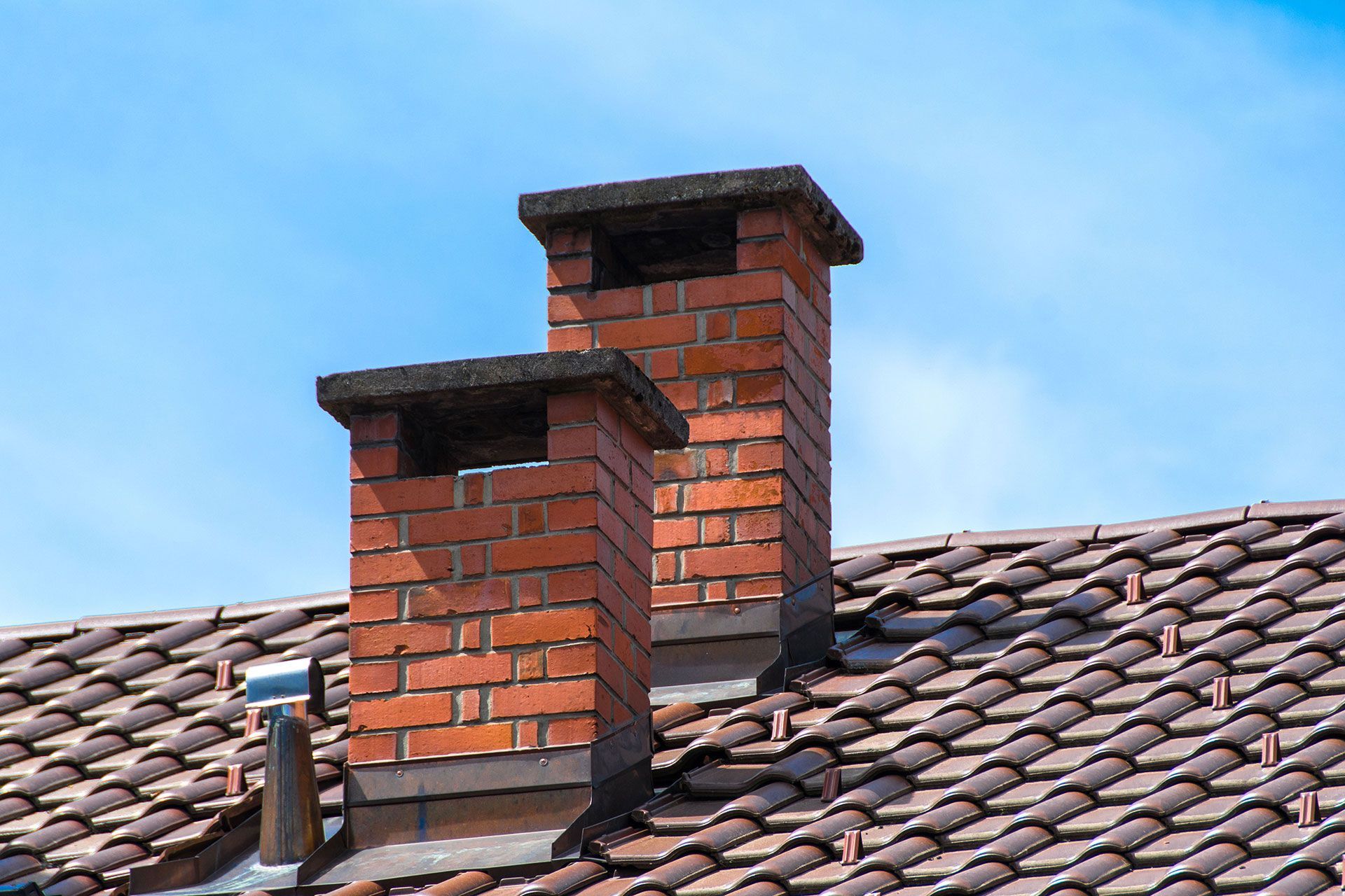 Two brick chimneys on top of a tiled roof