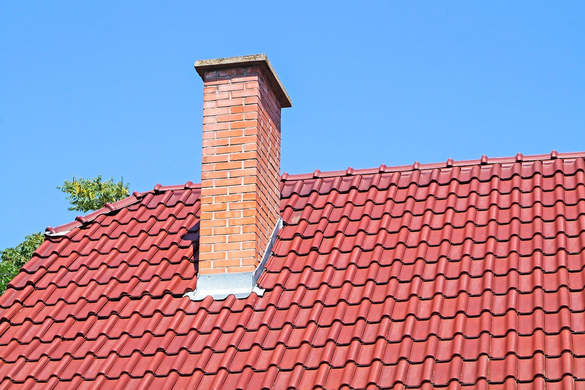 A brick chimney on top of a red tiled roof