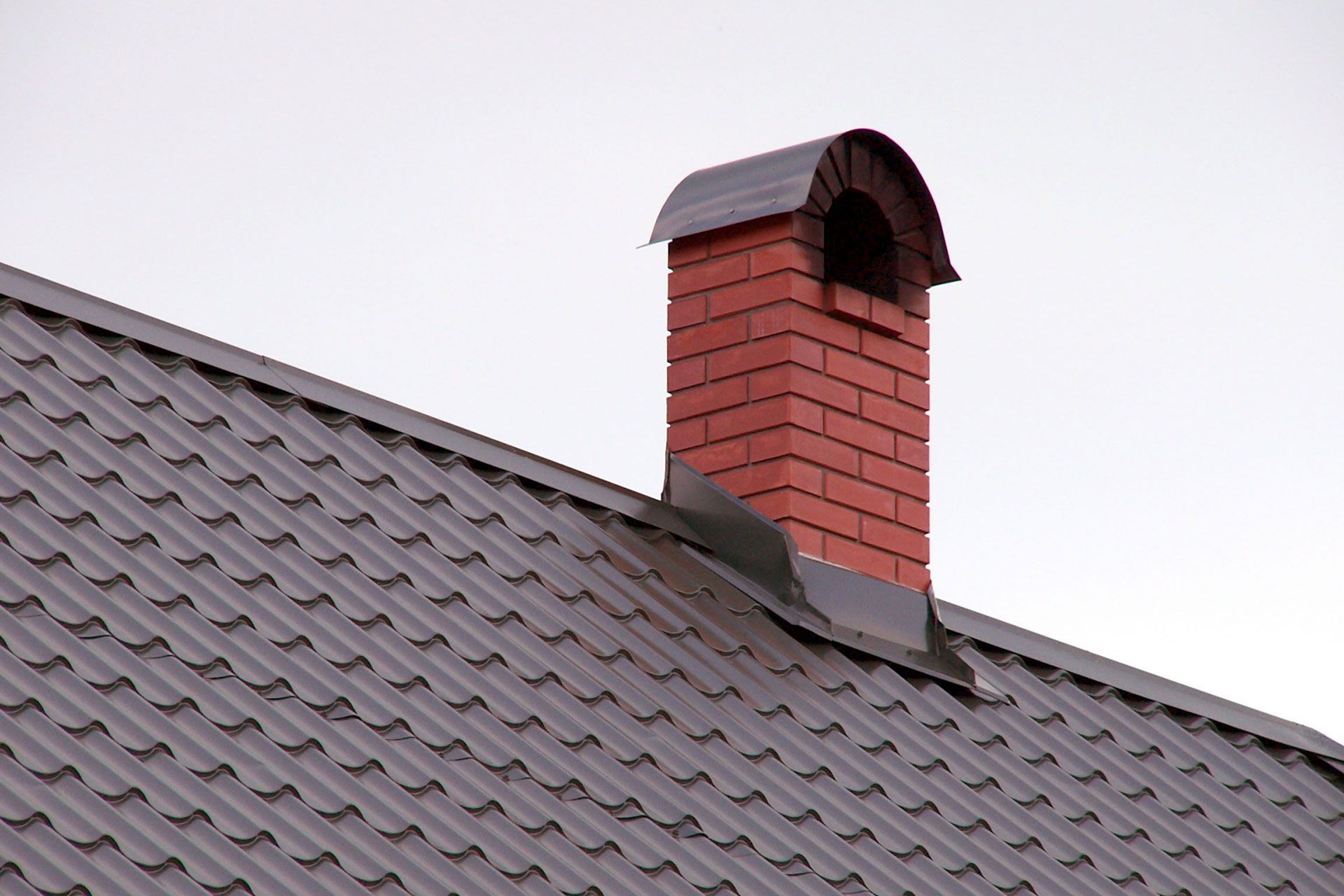 A brick chimney is on the roof of a house 