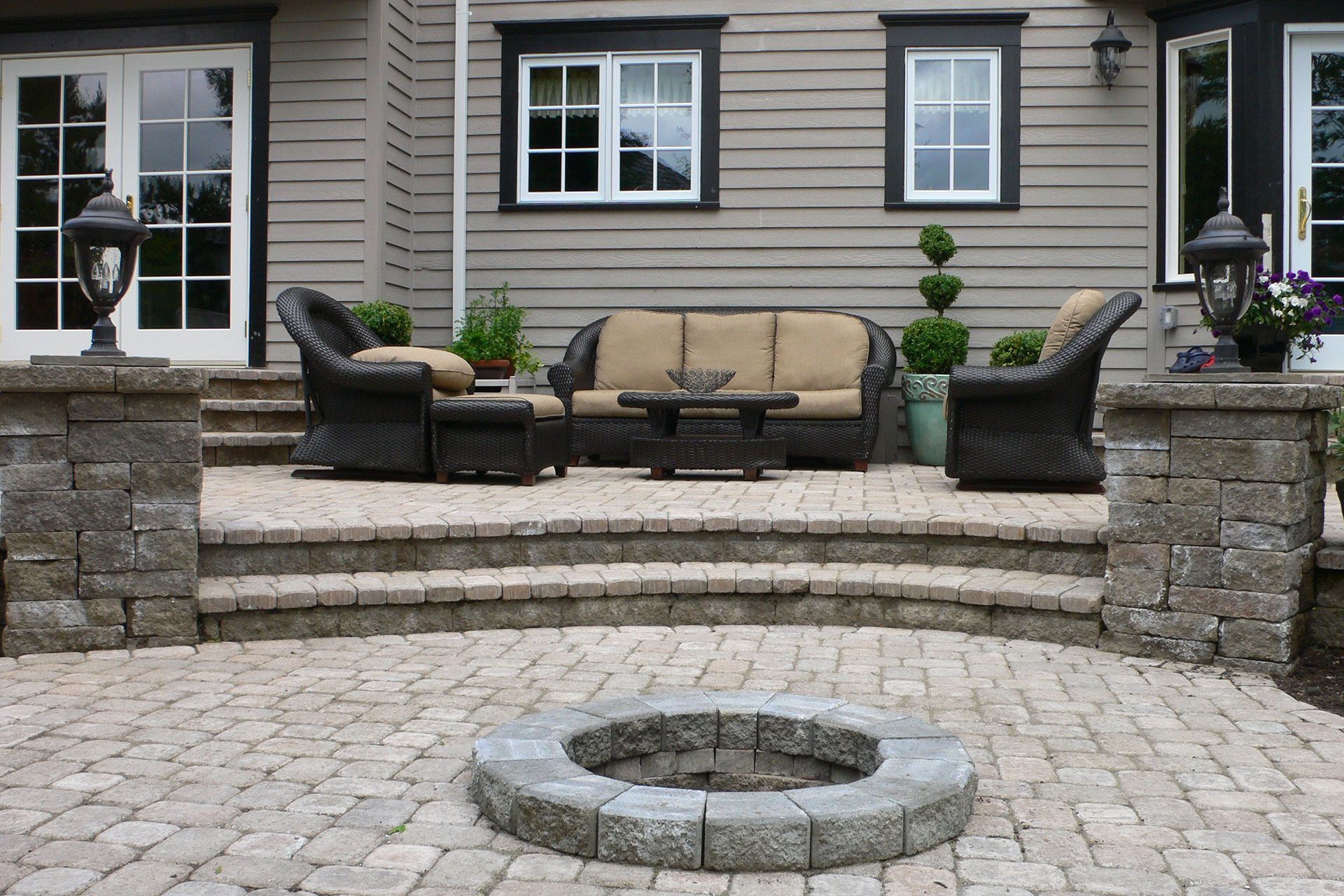 A patio with a fire pit and furniture in front of a house