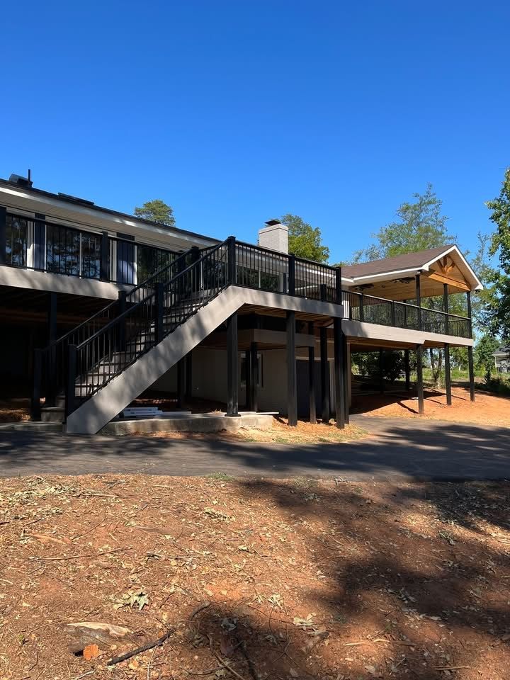 Modern two-story building with a metal staircase, deck, and covered porch in a dry wooded area